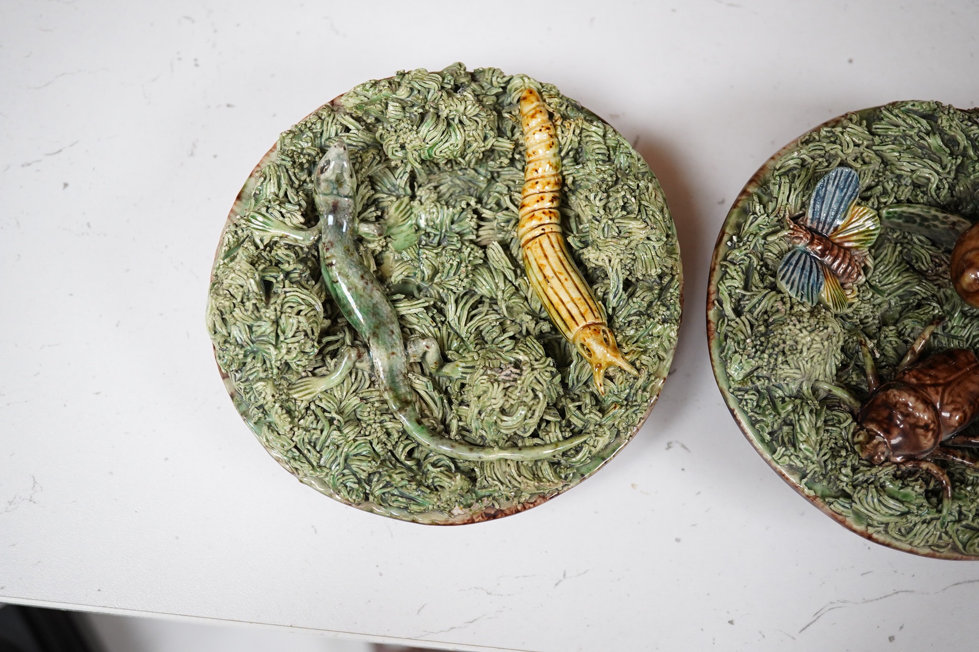 A pair of late 19th century Portuguese small circular Palissy style majolica plaques incorporating lizard and snail and with a mossy ground, impressed marks to reverse, 12cm diameter. Condition - fair